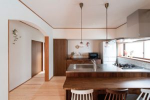 天然木のシステムキッチンに合わせたデザインで家電もしまえるパントリーを造作