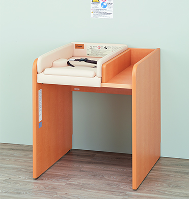 バッグや小物が置ける荷物台が一体となったおむつ交換台。寝返りしにくい両サイドガードと手前へのずれ防止のフットガードを装備したホールディングマットを採用。