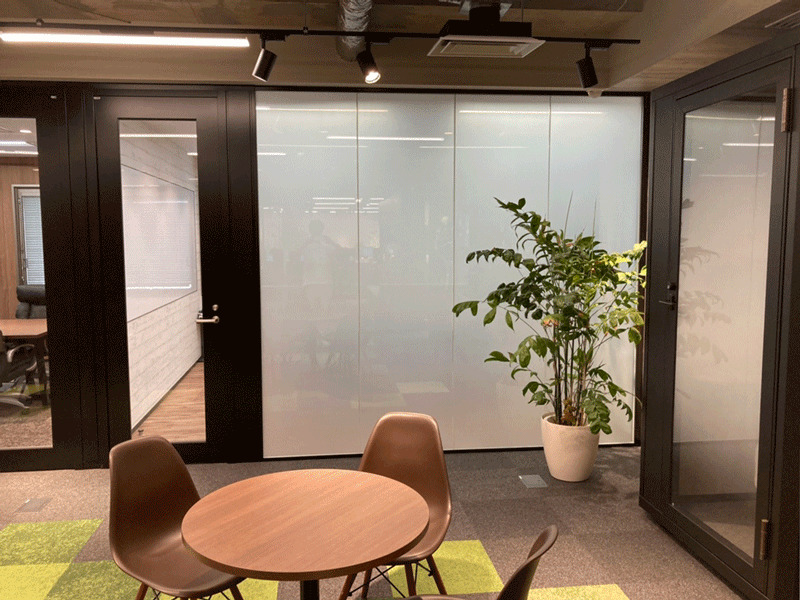 オフィス会議室での調光フィルム施工事例。ガラスの開放感を生かしつつ、必要な時だけプライバシー保護ができるため、来客時や会議の際に有用である。